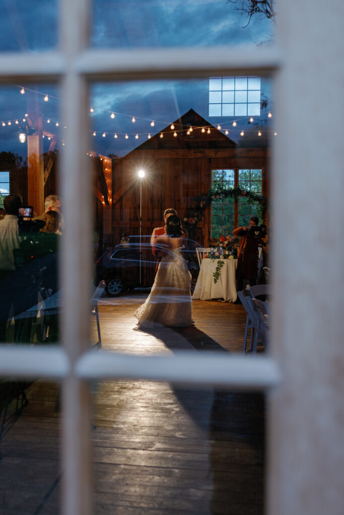 A couple doing their first dance, seen through a window. 